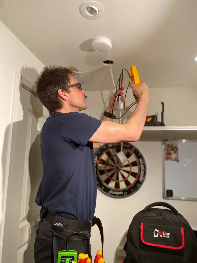 Elektriker installerar takbelysning och mäter vid takuttaget