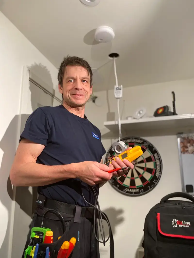 Elektriker mäter vid takuttag under elarbete i Norrort