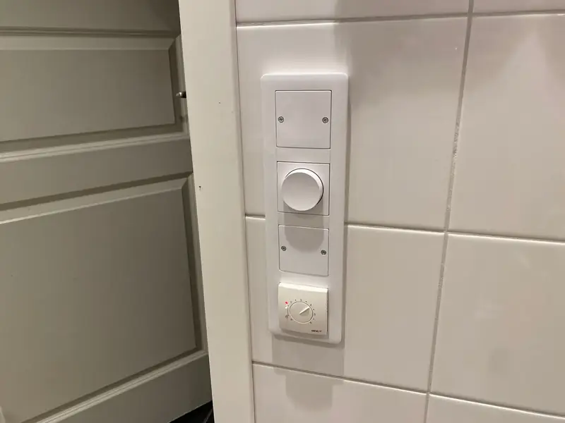 Nymonterad dimmer och strömbrytare på kaklad vägg